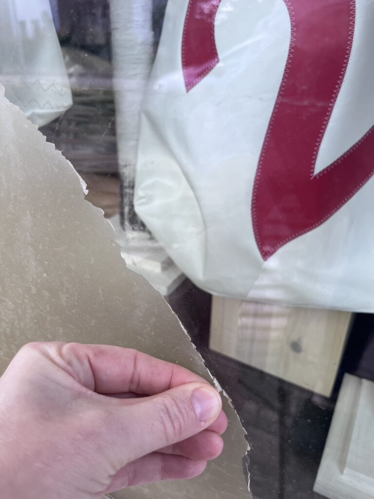 Hand knibbelt einen Kleber von der Schaufensterscheibe